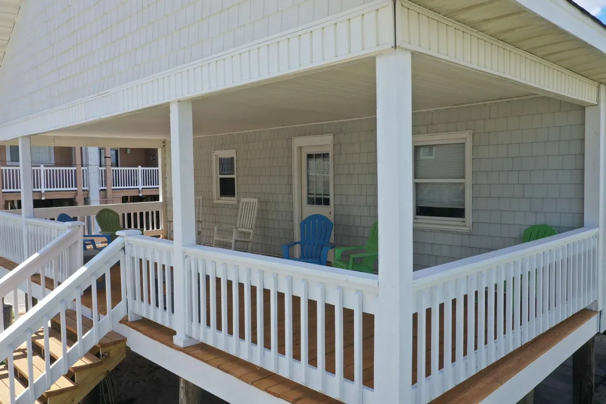 A cheerful exterior shot featuring the porch with colorful chairs and shingle siding. The scene exudes a lively, welcoming vibe and suggests a place to unwind, host barbecues, or enjoy a good book in the sunshine. The presence of multiple chairs and the outdoor setup hint at a pet-friendly, family-oriented space.