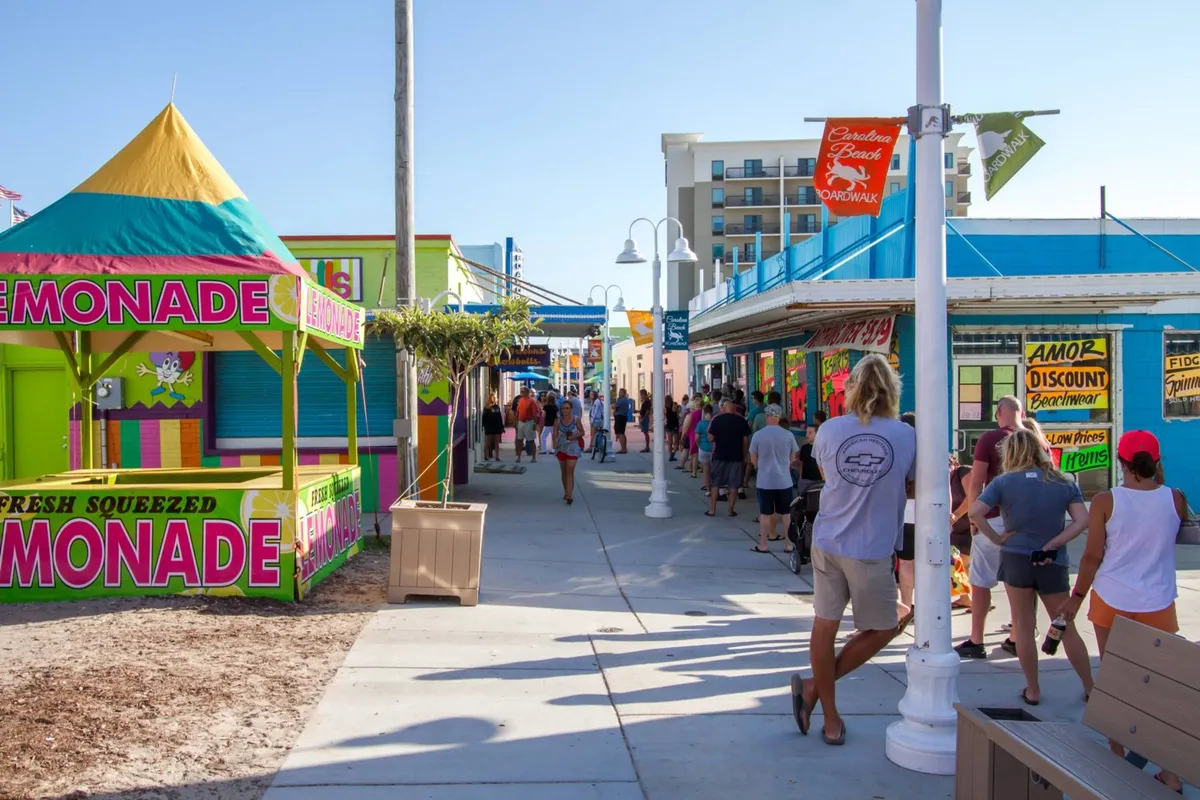 A festive street scene with a lemonade stand, colorful storefronts, and a lively crowd enjoying food, shopping, and social interaction. The vibrant, energetic vibe captures the heart of a walkable, fun neighborhood with plenty to explore just outside the door.